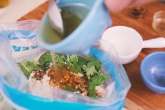 Ngò rí cắt nhỏ, cho vào túi cánh gà cùng 1 muỗng canh nước mắm, 1 muỗng canh nước tương, 30ml mật ong, 1 muỗng cà phê tỏi băm, 1 muỗng canh dầu mè vào, trộn đều.
