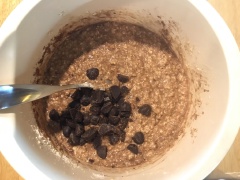 Cho bột caocao và baking soda cùng bột nở vào. Trộn một lần thật nhanh nữa rồi cho chocolate chip vào. Lót khuôn muffin vào khay muffin. Nếu không có khuôn giấy muffin thì bạn có thể cắt giấy nến rồi lót vào như hình.