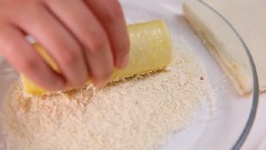 Nhúng bánh mì cuộn xúc xích vào chén trứng gà đánh tan, lăn qua bột chiên xù.