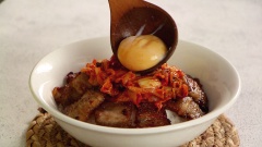 Cho cơm trắng vào tô, xếp thịt ba chỉ xung quanh, cho thêm kim chi, 1 lòng đỏ trứng đã chần sơ, rắc thêm một ít mè rang, rưới thêm nước sốt kim chi là đã có được một món ăn ngon cho cả gia đình.