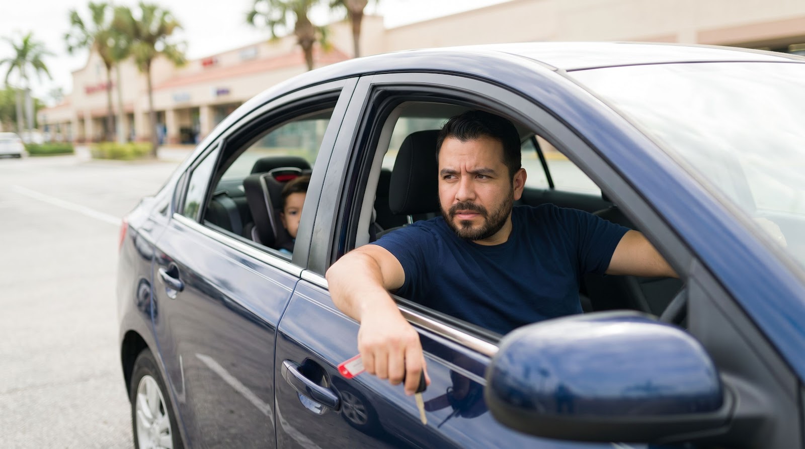 Hispanic father in a blue car thinking about uninsured drivers and whether Florida PIP coverage is enough