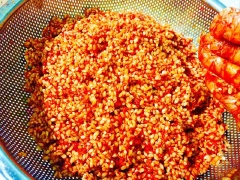 Trộn đều gạo nếp với hỗn hợp gấc để gạo nếp chuyển qua màu cam đậm.