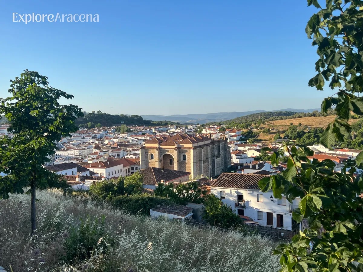 Panoramic view of Aracena from the castle hill, showing white buildings, rooftops, and the surrounding green landscape.