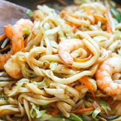 Tiếp theo cho tôm, hành lá vào xào 1 - 2 phút rồi mới thêm mì udon vào. Nêm nếm gia bị đã chuẩn bị gồm nước tương, dầu hào, rượu vang, hắc xì dầu, muối, đường cho thật vừa miệng nha. Xào mì khoảng 2 - 3 phút nữa cho thấm gia vị thì tắt bếp. Cho mì ra dĩa, rắc chút mè rang lên trên là có ngay món ngon rồi đó.