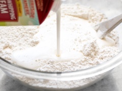 Mở lò trước ở 200 độ C. Trong âu lớn trộn 300g bột mì, muối, đường và bột nở với nhau. Sau đó cho 500ml heavy cream vào bột và trộn thật đều, nhào bột đến khi thành khối bột dẻo mượt. Tạo bột thành hình chữ nhật và chia thành 12 miếng bằng nhau.