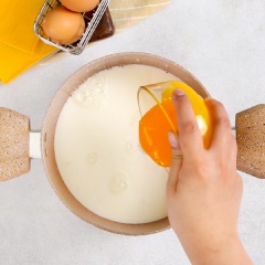 Cho 600ml sữa tươi không đường, 60gr đường, 4 cái lòng đỏ trứng, 1 muỗng canh vani, 60gr bột bắp vào nồi khuấy đều cho bột tan hết. Sau đó, bắc nồi lên bếp, cho tiếp 3 lát phô mai vào rồi nấu ở lửa nhỏ đến khi hỗn hợp đặc lại, luôn khuấy đều tay trong lúc nấu.