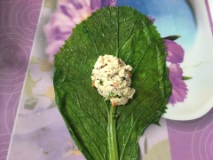 Trải lá cải ra mâm, múc khoảng 1/2 muỗng canh hỗn hợp nhân đậu hũ cho vào, gấp mép lá lên 2 lần sau đó cuốn tròn lại rồi cột bằng cọng hành. Cho các túi cải bọc đậu hũ lên xửng hấp lửa lớn khoảng 15 phút.