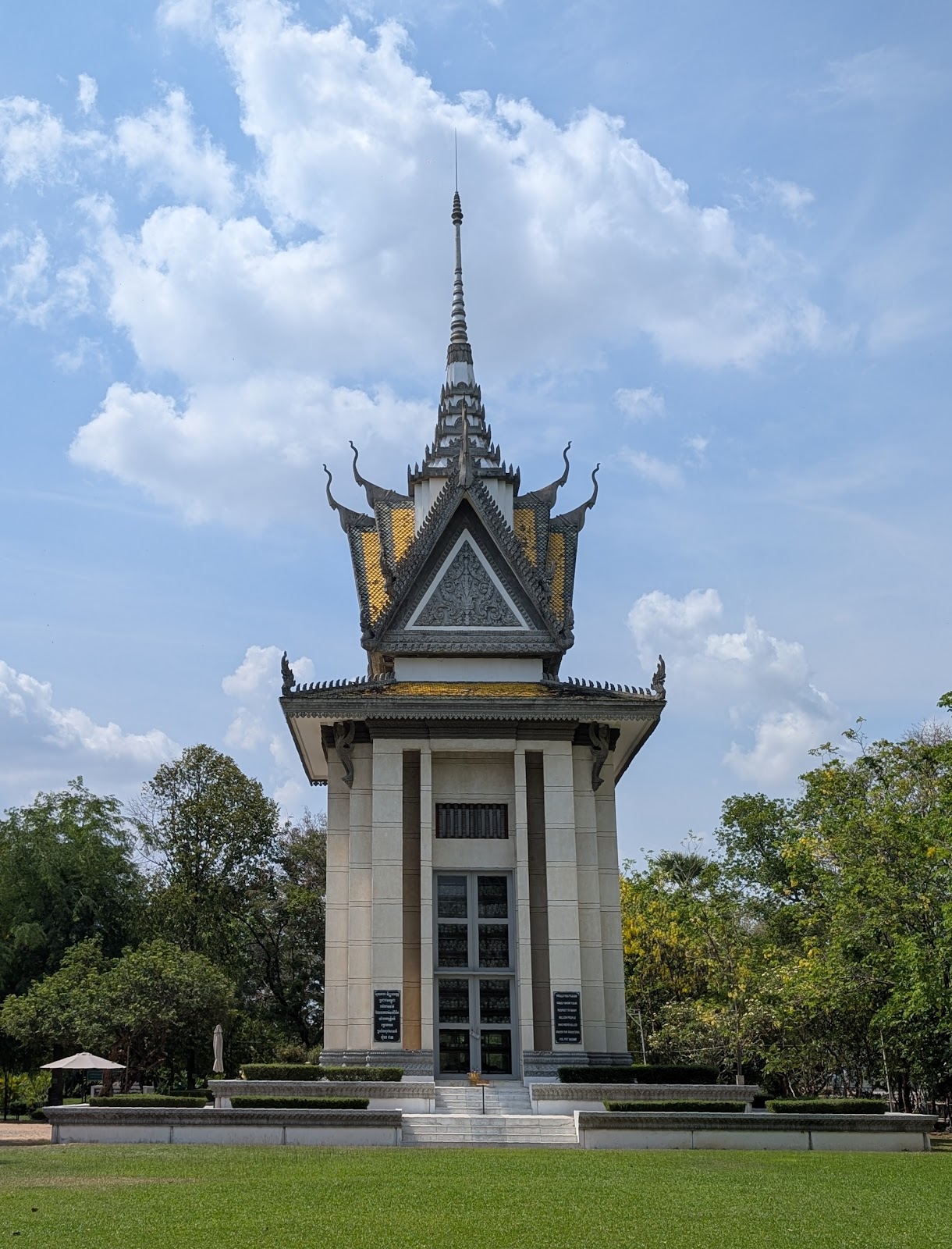 Tall building with white stone walls, gold roof tiles, and
                 large front windows through which you can just see stacked
                 human bones