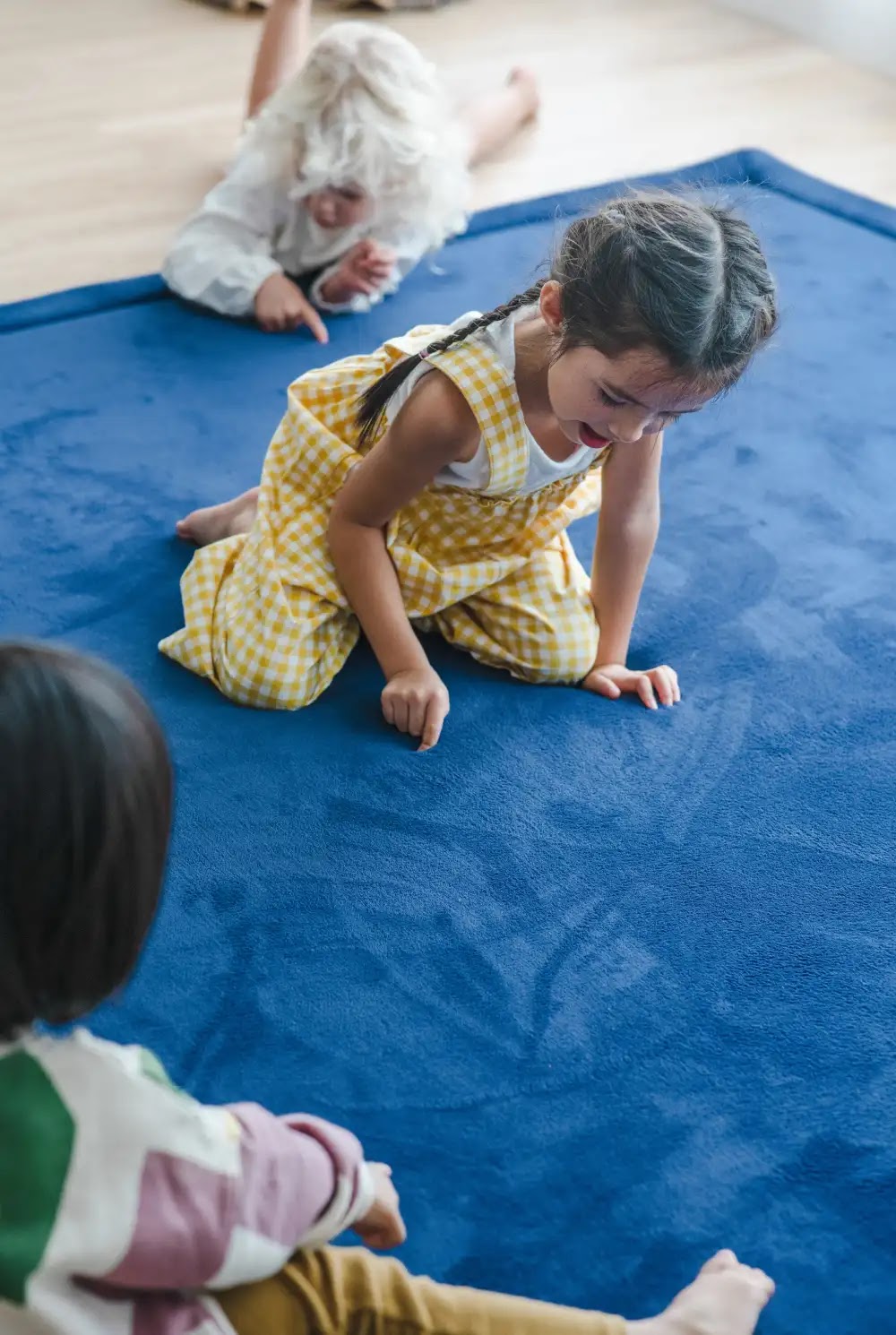 Young girls playing on a thick navy baby room rug laid over a hard wood floor