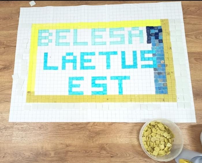 Elaboración dun mosaico co lema 'Belesar Laetus Est' con teselas de cores