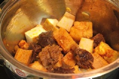 Cho đậu hũ, bắp bò vào nồi, thêm nước mắm, đường, muối, hạt nêm, hành tím băm và ớt trái đặt lên bếp đun sôi thì đổ nước luộc bắp bò vào nồi. Tiếp tục đun đến lửa nhỏ đến khi bắp bò mềm hẳn, nêm gia vị lại cho vừa miệng.