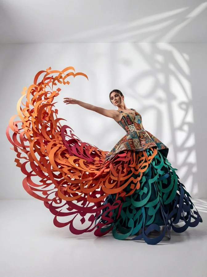 Fotografía de cuerpo entero: Mujer en pose dinámica con un vestido conceptual de vanguardia y falda con caligrafía en 3D.