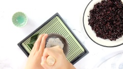 Sau khi xôi nếp cẩm chín thì cho xôi ra đĩa (hoặc mặt phẳng), dàn mỏng lớp xôi cho nhanh nguội. Giã mịn men nở rồi rắc đều vào xôi, vừa rắc vừa trộn đều để men và xôi hòa lẫn vào nhau. Bạn nên cho từng ít men vào trộn để đảm bảo lượng men được hòa tan đều vào nếp.