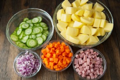 Chuẩn bị các nguyên liệu. Thịt nguội thái nhỏ. Khoai tây, cà rốt làm sạch, cắt nhỏ, luộc chín. Dưa leo, hành tây tím rửa sạch, dưa leo thái lát mỏng, hành tím thái nhỏ. Rắc 1/4 muỗng canh muối vào dưa leo và hành, đảo đều rồi để yên cho muối ngấm. Cho mayonnaise, giấm gạo, đường, 1/2 muỗng canh muối vào tô rồi trộn đều lên để làm phần sốt.