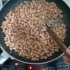 Lựa bỏ hạt đậu hư, rửa sạch với nước và để thật ráo. Bắt 1 cái chảo lên bếp, đun nóng chảo, cho vào chảo 2 muỗng canh muối (mục đích: khi cho muối vào khi rang đậu giúp hạn chế đậu tiếp xúc trực tiếp với đáy chảo gây cháy, nhiệt độ ổn định giúp hạt đậu vàng đều hơn). Cho đậu phộng đã ráo nước vào rang đều tay ở lửa nhỏ.