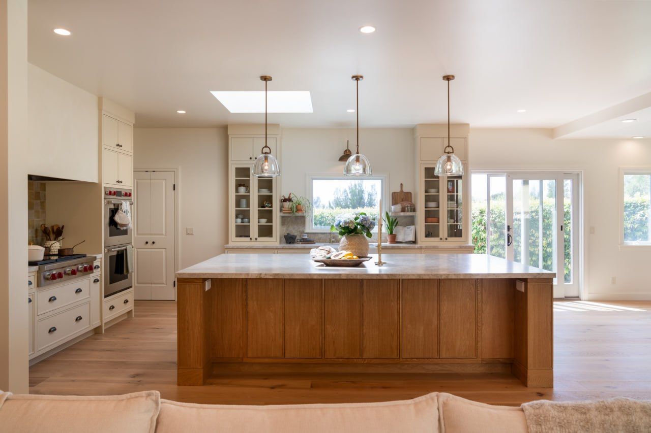 Kitchen island with oak base, brass pendant lights, and skylight above