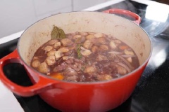 Cho hành tây, cà rốt, nấm vào xào. Cho bột mì, rượu mạnh vào đảo lại lần nữa. Thêm thịt gà, thịt xông khói, tương cà, rượu vang đỏ, nước dùng gà, cỏ xạ hương, lá nguyệt quế vào đun sôi. Đậy vung, đun tiếp khoảng 20-30 phút trong lửa nhỏ cho đến khi thịt gà mềm thì tắt bếp.