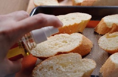 Cắt bánh mì thành từng miếng xéo nhỏ. Sau đó phết dầu ăn lên phía trên rồi đem đi nướng ở 180 độ C trong vòng 15 phút.