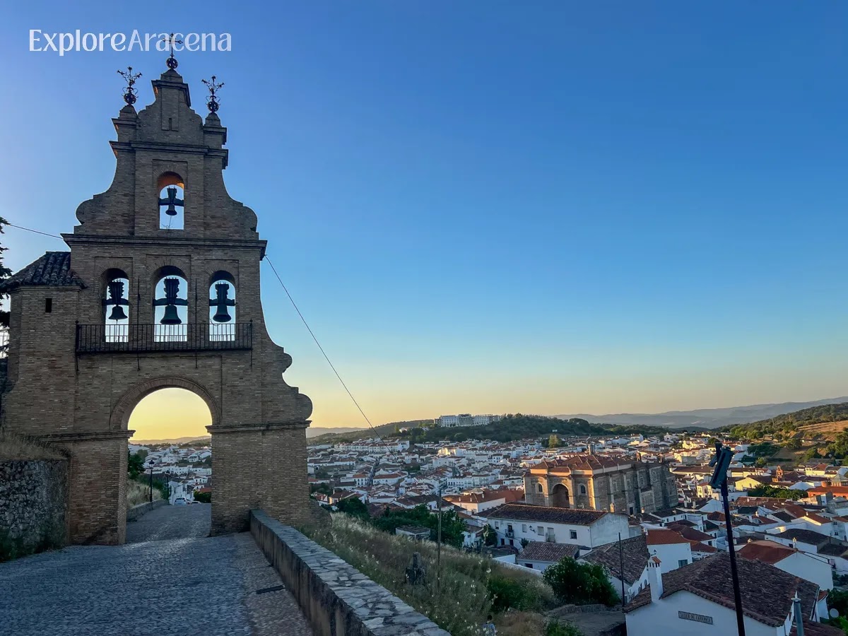 Stone archway on the route to Castillo de Aracena with bell tower and town views visible through the opening.