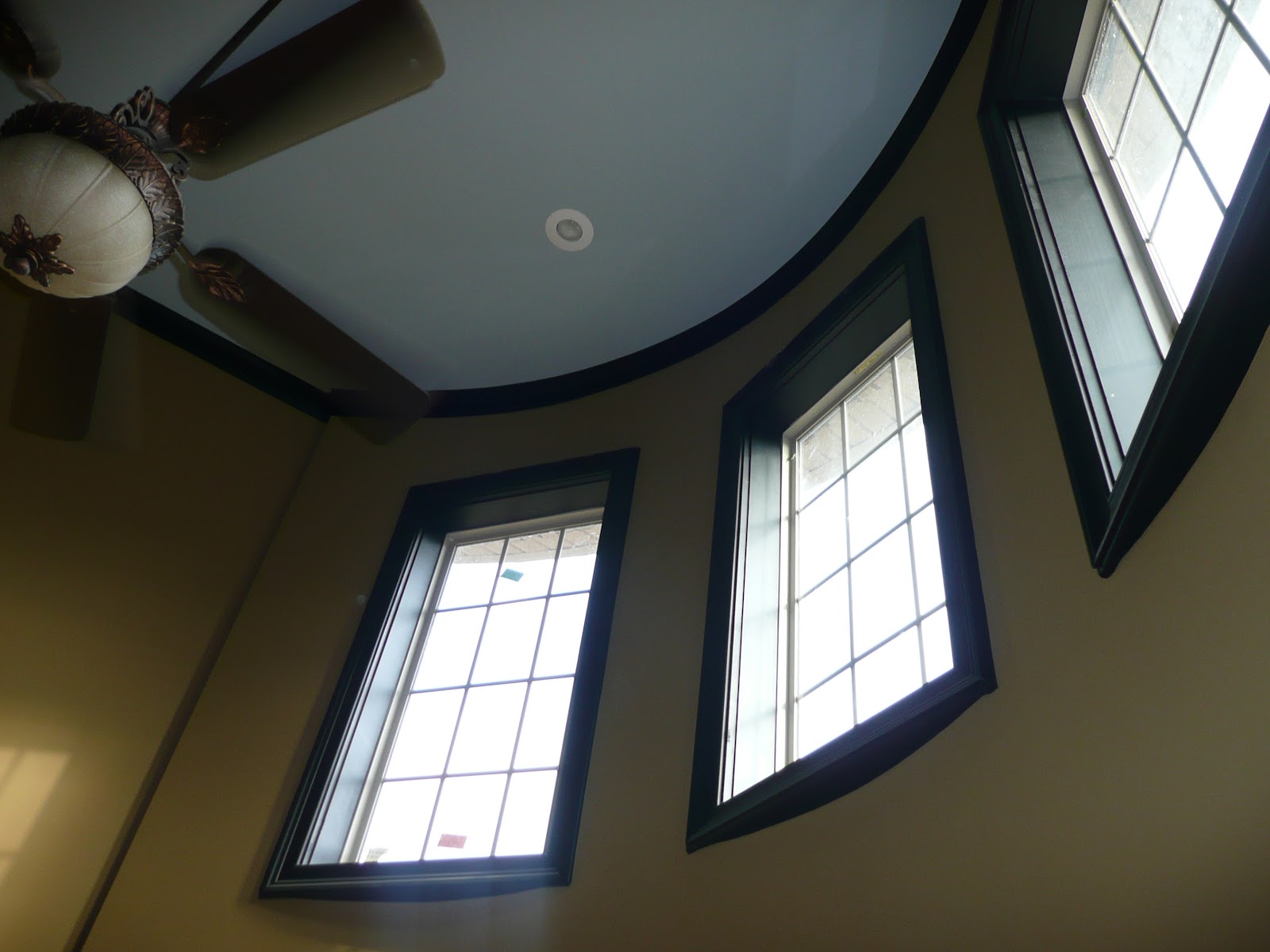 Low-angle view of a curved wall with three tall windows and a light blue curved ceiling.
