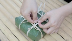 Buộc sơ dây lạc có sẵn để cố định bánh chưng. Sau đó lần lượt buộc thêm 2 dây ngang, 1 dây dọc (có thể thêm 3 dây ngang, 2 dây dọc cũng được). Có thể cắt bỏ bớt dây thừa cho bánh chưng xanh ngày tết được gọn và đẹp hơn.