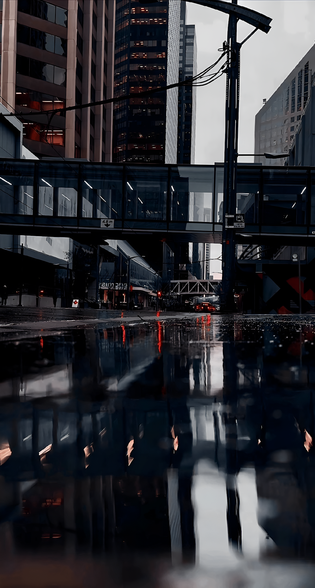 Rainy City Street with Skyscraper Reflections in Puddles - Free 4K mobile Wallpaper