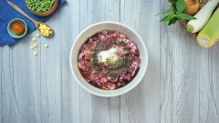 Cho 500gr thịt bò xay trộn cùng 100gr giò sống và 50gr mỡ heo, ướp gia vị với 1 muỗng canh tỏi băm, 1 muỗng canh hạt nêm, 1 muỗng canh đường, 2 muỗng canh nước mắm, 1 muỗng canh tiêu, 1 muỗng cà phê dầu ăn. Cho 50gr bột bắp, 10gr bột nở vào 100ml nước lạnh, khuấy đều rồi cho vào hỗn hớp thịt vừa ướp. Nhồi đều tay cho gia vị hòa quyện rồi cho thịt vào túi zip hoặc khay to rồi dàn mỏng thịt, sau đó cho vào tủ đông để khoảng 3-4 tiếng.