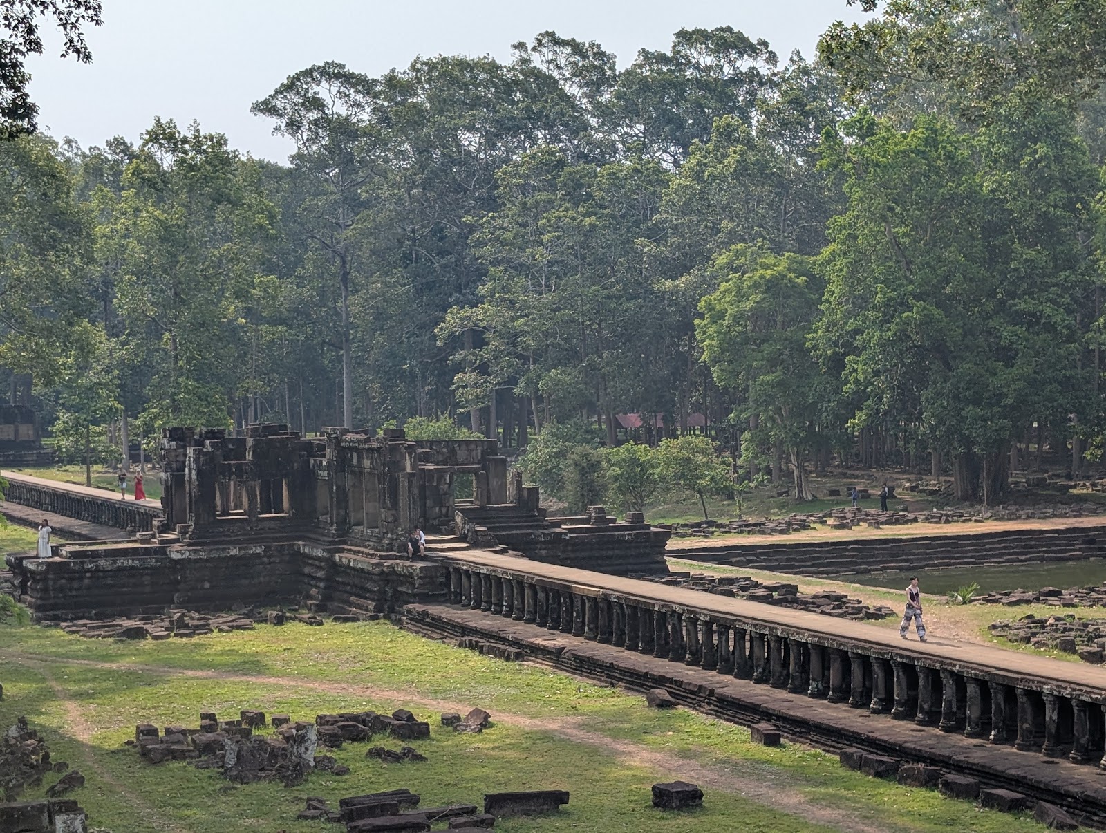 A photo looking down at a temple that has a raised walkway
                 made of stone extending to the right of the photo
