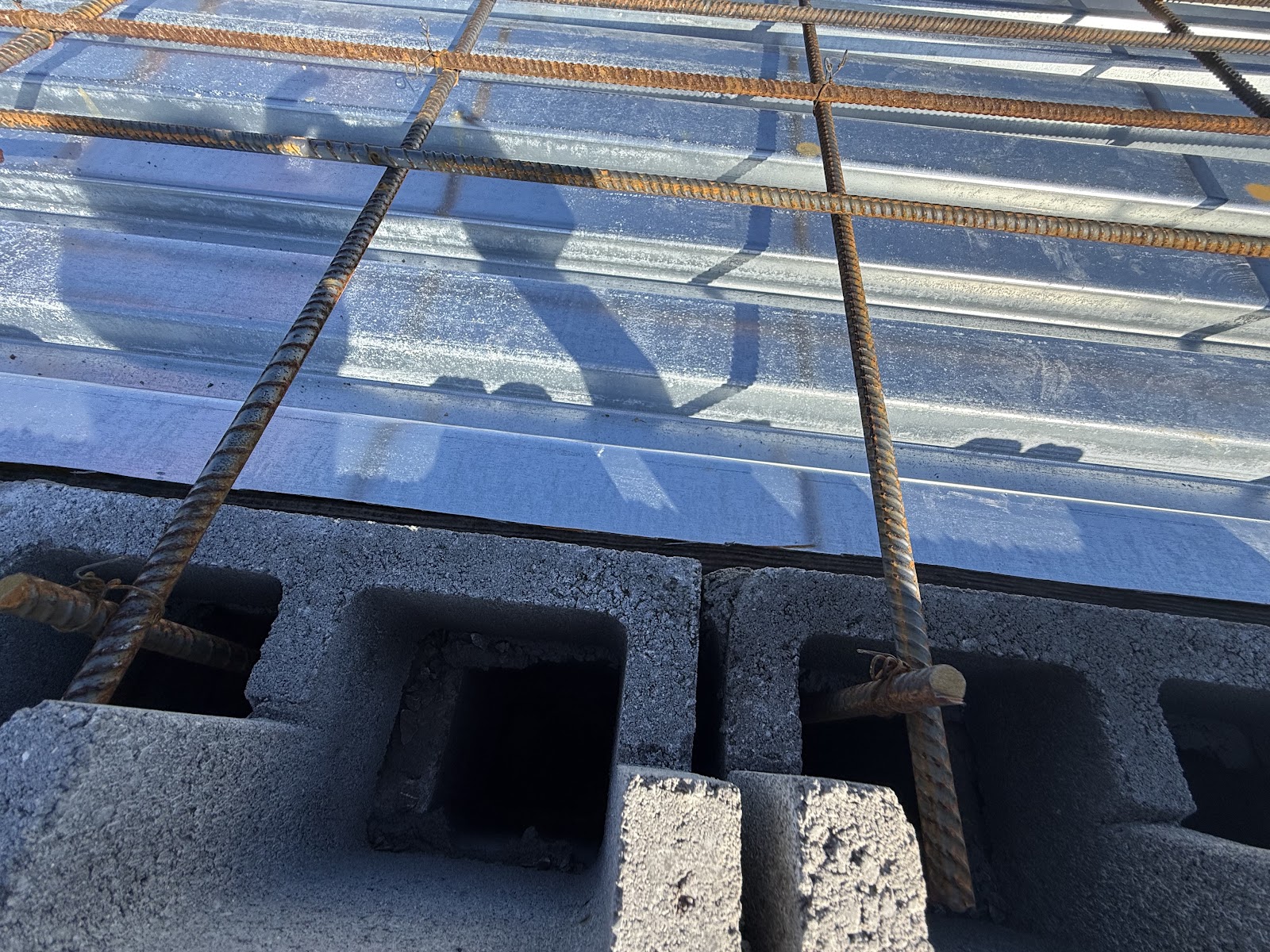 Detail of rebar reinforcement connecting to the concrete block walls and metal decking of a storm shelter.