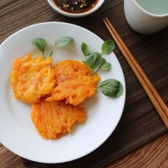 Cho bí đỏ tẩm bột chiên giòn ra đĩa, bày trí đẹp mắt. Trong chén nhỏ pha chế thức chấm gồm: 1 muỗng canh nước tương, 2 muỗng canh nước lọc, 1/2 muỗng canh giấm và 1 trái ớt băm.