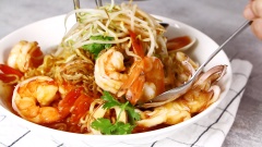 Cho lần lượt mì gói, tôm, mực, nghêu và giá, rau thơm vào tô. Rưới nước sốt chua cay vào. Thêm hành phi và dùng đũa trộn đều để các nguyên liệu thấm sốt.