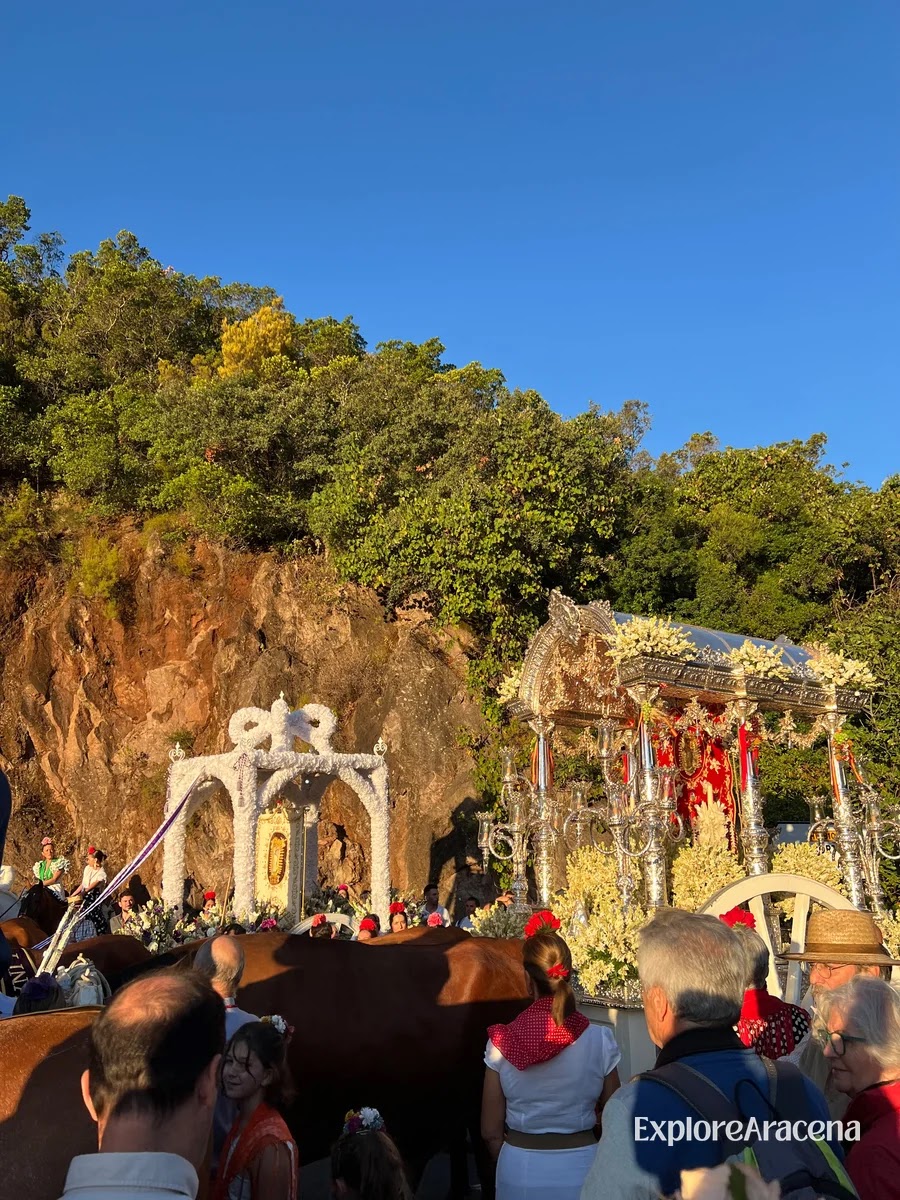 Floral arches and a silver religious float beside the rocky cliff at the Peña de Arias Montano