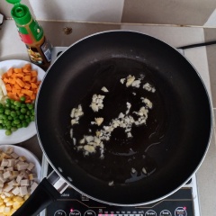 Làm nóng một chảo khác cùng 2 muỗng canh dầu, cho tỏi vào phi thơm, sau đó cho cà rốt và đậu hòa lan vào xào chín, tiếp đến cho hành tây và chả lụa vào xào cùng.