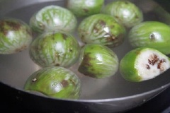 Cà đắng xanh bổ làm đôi, ngâm cà qua thố nước muối pha loãng, sau 15 phút vớt ra rửa lại nước lạnh cho sạch, để lên rổ cho ráo nước.