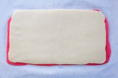 Cho miếng bột màu trắng lên trên miếng hồng, cán nhẹ cho 2 miếng bột dính vào nhau, cắt bỏ phần rìa dư. Cuộn miếng bột lại, sao cho thành hình trụ tròn. Dùng giấy nến bọc khối bột lại, đem cất ngăn đá tủ lạnh trong 2 giờ hoặc qua đêm cho cứng lại.