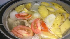 Rửa sạch xương gà, nấu sôi 3 lít nước cho xương gà vô hầm, vớt bọt cho nước dùng trong. Trong lúc hầm xương thì đi sơ chế rau củ: thơm cà chua, hành tây rửa sạch cắt lát, rau sống lặt rửa sạch. Hầm xương gà được 20 phút thì cho thơm, cà chua, hành tây vô hầm thêm 10 phút.
