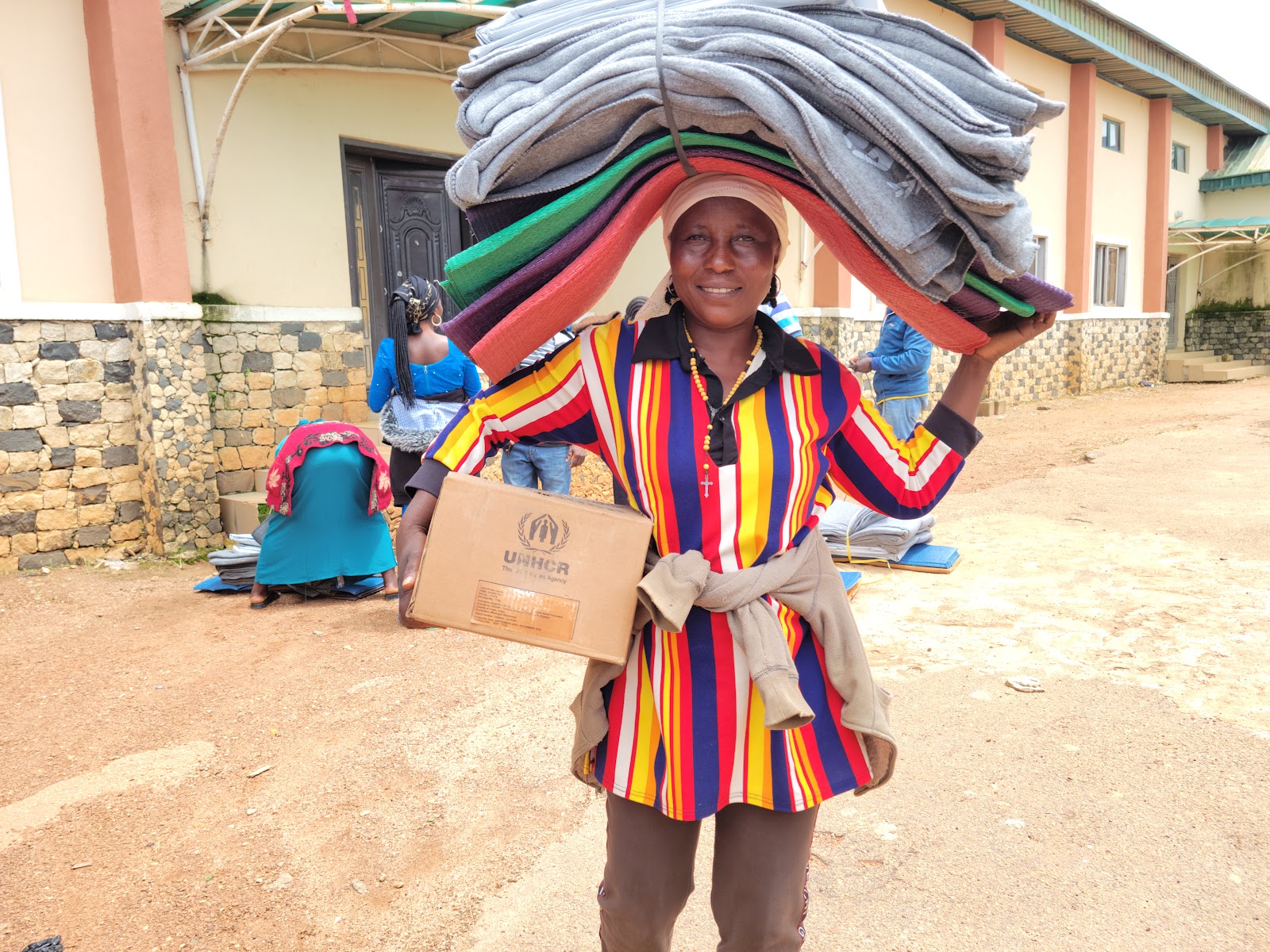 A beneficiary carries blankets and a UNHCR relief package following the distribution of essential non-food items to vulnerable households in Plateau State.