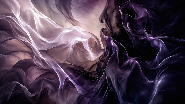 Dynamic billowing folds of dark purple and semi-sheer lavender fabric in ambient light.