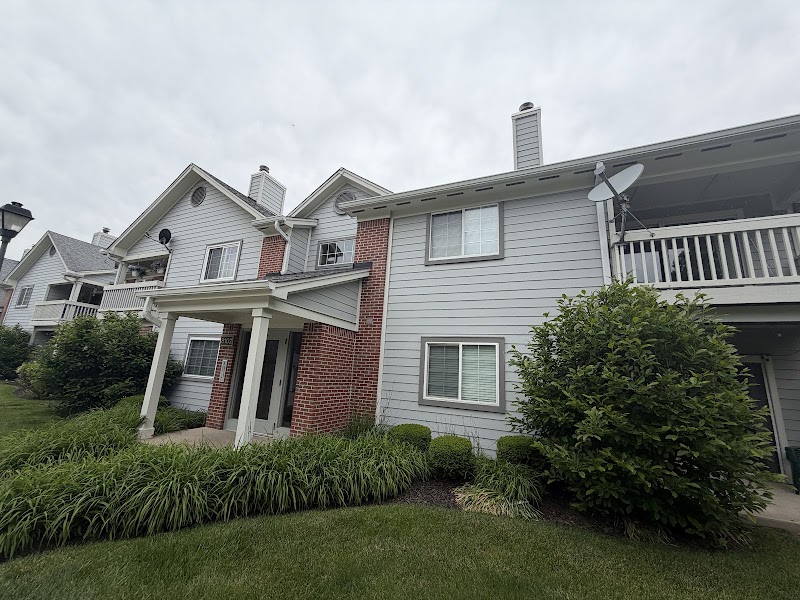 Hidden Creek Condominiums building before the repaint, white siding with balconies and a brick entry