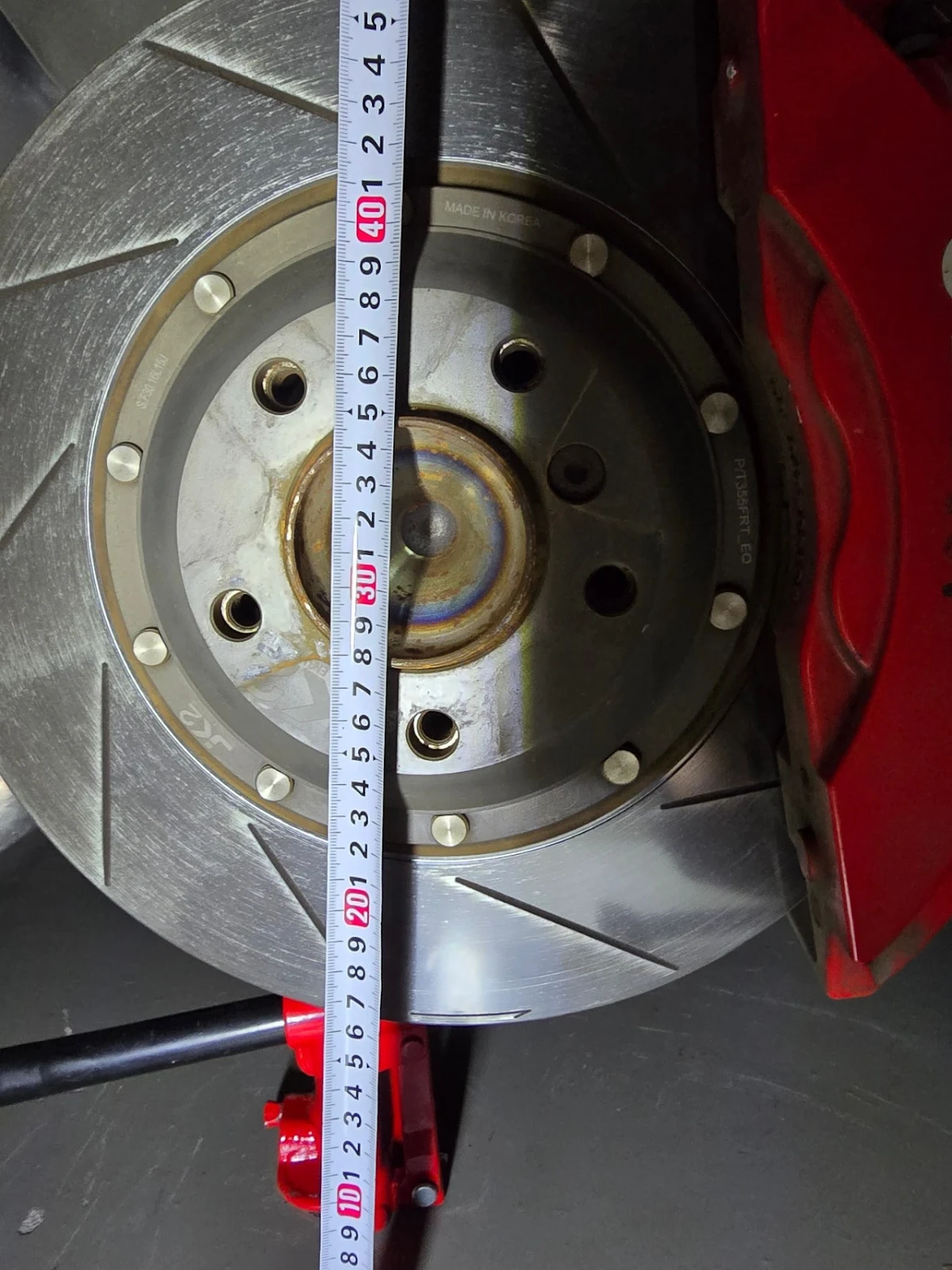 BMW Z4 E89 공차 체결 전 지상고 측정 — 펜더에서 휠 센터까지 높이를 줄자로 측정하는 모습