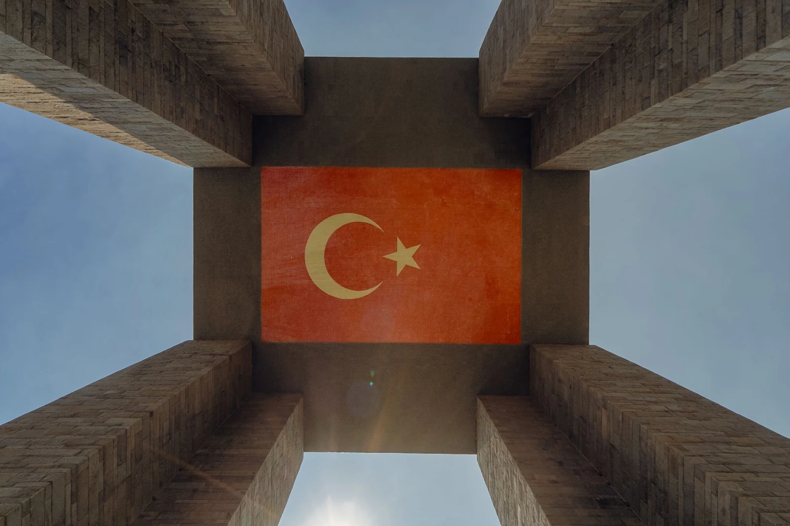 Upward view of the Çanakkale Martyrs' Memorial featuring the Turkish flag against the sky.