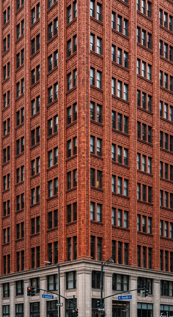 Close-Up of an Ornate Orange Terracotta Skyscraper Corner with Repeating Window Pattern