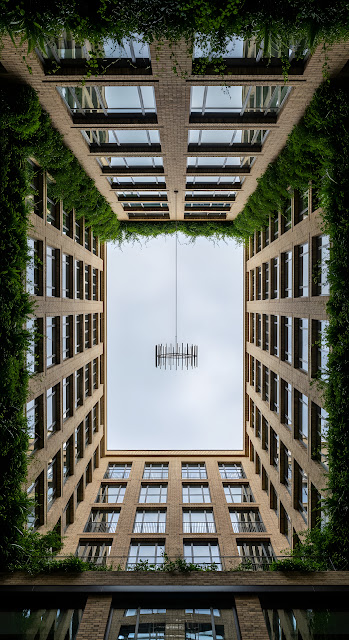 Symmetrical Low-Angle View of Modern Brick Architecture Forming an Urban Canyon with Hanging Foliage - Free mobile Wallpaper