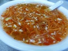 Trong 1 chén trộn đều 2 muỗng canh nước mắm, 1 muỗng canh nước sôi, 1/2 muỗng canh đường, 1/2 muỗng cà phê tỏi băm, 1/4 muỗng cà phê ớt băm và 1 muỗng cà phê nước cốt chanh để làm nước chấm. Thêm đồ rau củ ngâm chua vào chén nước chấm để ăn cùng.