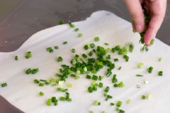 Khi bột đã nghỉ đủ thì lấy ra, nhào thêm lần nữa rồi chia bột thành các phần bằng nhau, cán thật mỏng bột sau đó phết dầu bột vừa trộn lên trên, rắc hành lá đã xắt nhỏ lên rồi cuộn lại như hình rồi cán mỏng bột thêm một lần nữa.