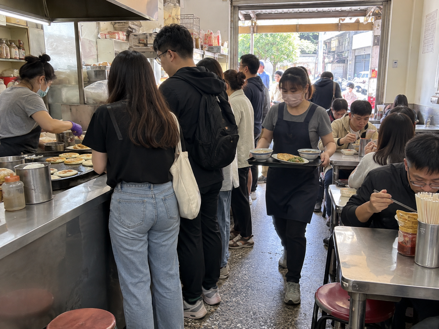 尖峰時段顧客排隊與員工送餐共用通道，形成早餐店動線瓶頸