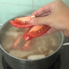 Nấu sôi nước me và măng, hớt bớt bọt nổi trên mặt để nước canh được trong. Cho cá basa đã làm sạch vào nấu chín, để canh sôi thêm 1 lần nữa thì cho cà chua vào.