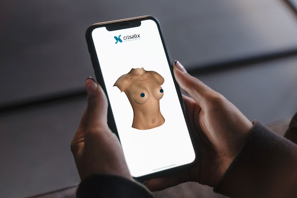 Des mains tenant un smartphone affichant une simulation 3D dans l’application Crisalix.