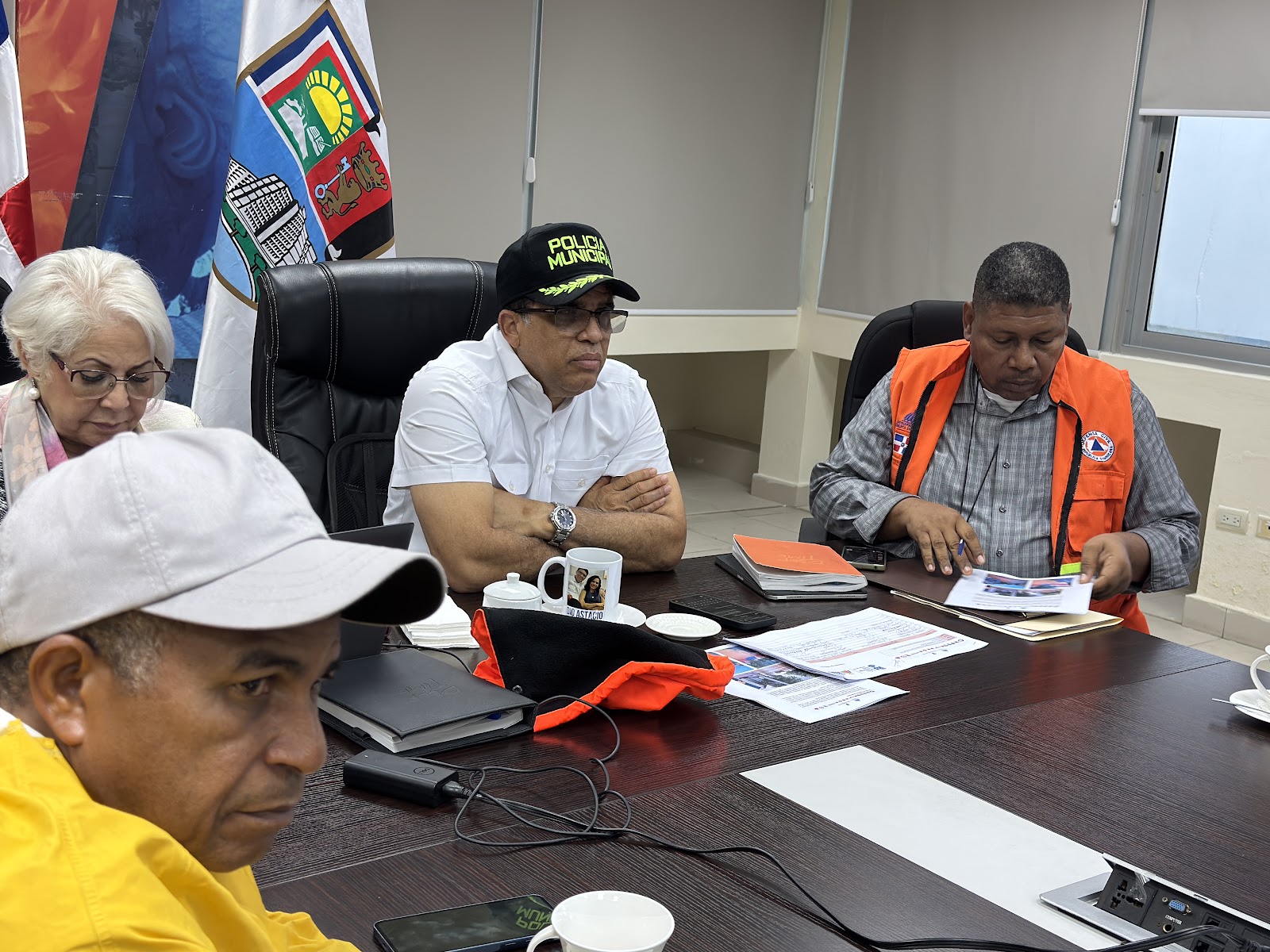 Dío Astacio y Defensa Civil revisando documentos en la reunión