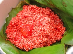 Gạo nếp vo sạch, trộn đều với 70g thịt gấc. Sau đó gói vào lá chuối đặt trong lồng hấp của nồi cơm điện.